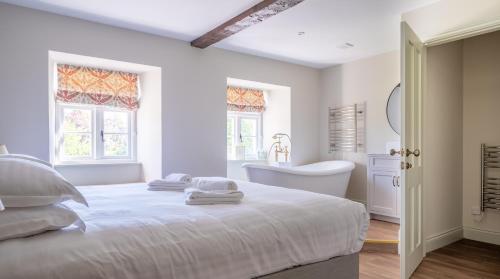 a white bedroom with a bed and a tub and a sink at Cunsey Mill House in Far Sawrey