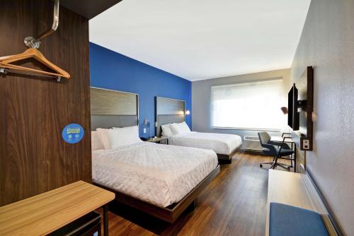 a hotel room with two beds and a blue wall at Tru By Hilton Huber Heights Dayton in Huber Heights
