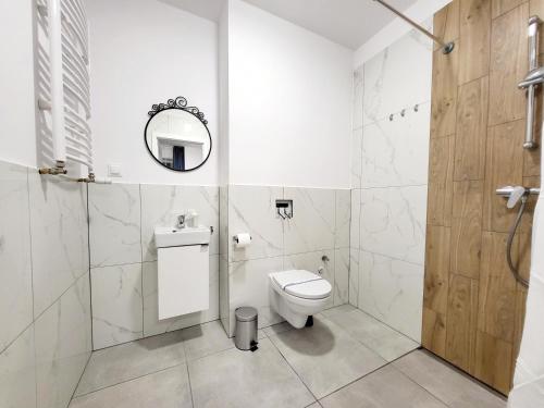 a white bathroom with a toilet and a mirror at Mini Apartamenty Poznań in Poznań