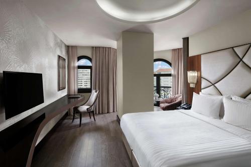 イスタンブールにあるDoubleTree by Hilton Istanbul Esentepeのベッド、デスク、テレビが備わるホテルルームです。