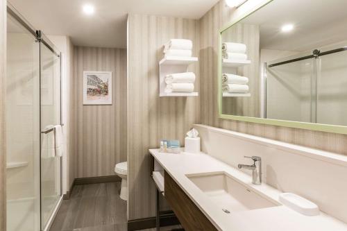 a bathroom with a sink and a mirror and a toilet at Hampton Inn & Suites by Hilton Québec - Beauport in Quebec City
