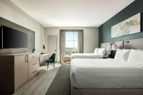 a hotel room with two beds and a flat screen tv at Hotel Alba Tampa, Tapestry Collection By Hilton in Tampa
