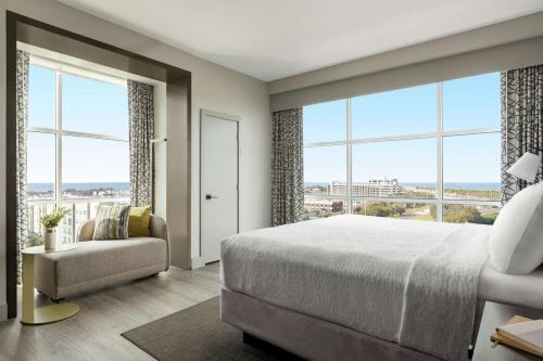 a bedroom with a bed and a chair and large windows at Hotel Alba Tampa, Tapestry Collection By Hilton in Tampa