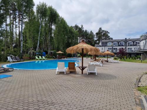 a swimming pool with chairs and umbrellas and a swimming pool at LA PERLA in Pobierowo