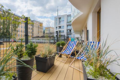 a balcony with two chairs and potted plants at Batorego 7 Apartament with Terrace & Parking Downtown Gdynia by Renters in Gdynia