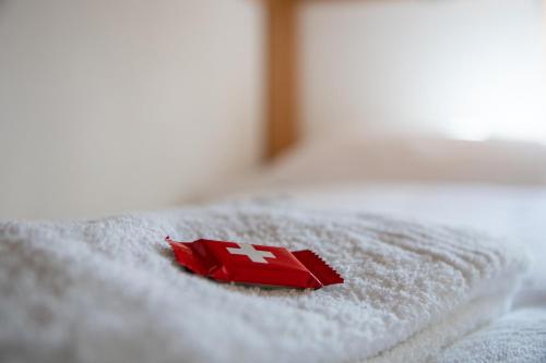 a red item on a white towel on a bed at Haus Bella Vista in Riederalp