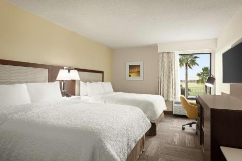 a hotel room with two beds and a window at Hampton Inn Houston Hobby Airport in Houston