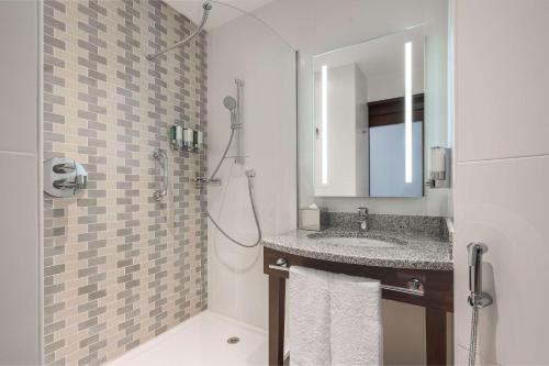 Hampton By Hilton Dubai Al Barsha في دبي: حمام مع حوض ودش مع مرآة