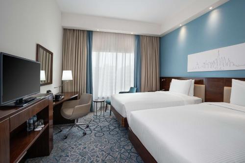 a hotel room with two beds and a flat screen tv at Hampton By Hilton Dubai Al Barsha in Dubai