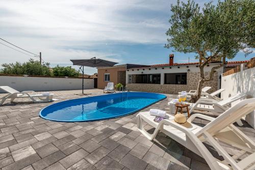 a swimming pool in a yard with chairs and a house at Villa Luma in Gorica