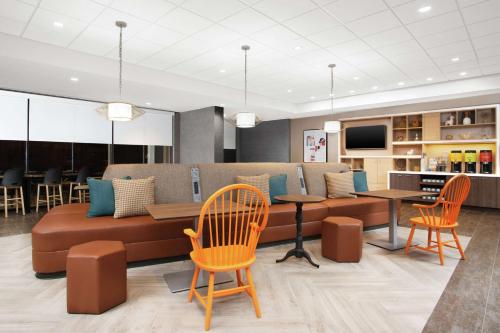 a living room with a couch and tables and chairs at Home2 Suites by Hilton Long Island Brookhaven in Yaphank