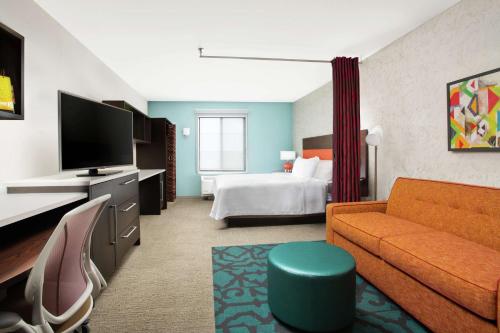 een hotelkamer met een bank en een bed bij Home2 Suites by Hilton Long Island Brookhaven in Yaphank
