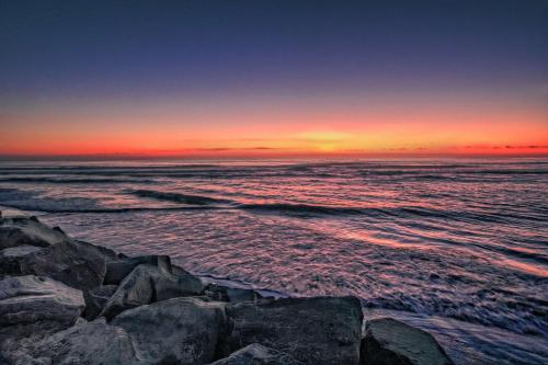 a sunset over the ocean with rocks in the water at Hampton by Hilton Encinitas-Cardiff Encinitas, CA in Encinitas