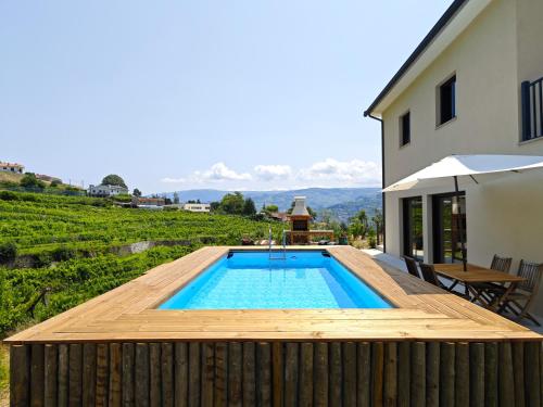 a swimming pool with a wooden deck next to a house at Casa da Milinha - Villa with a Pool near Rio Douro in Santa Cruz do Douro