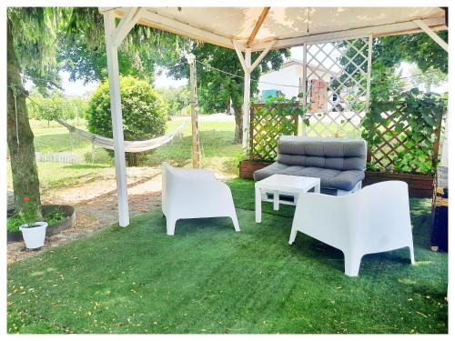 a patio with white chairs and a couch and a hammock at La Casina in Trecasali