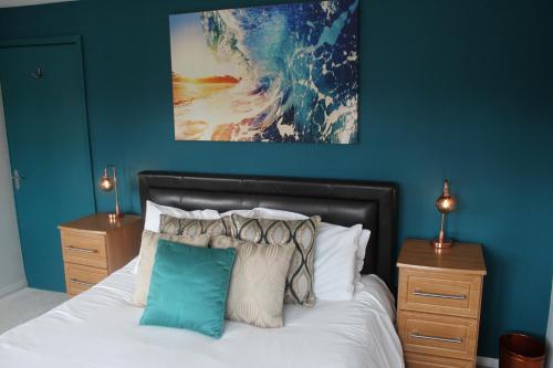 a bedroom with blue walls and a bed with pillows at Modern Property Near Chichester & Goodwood Events with Garden, Great for Families! in Chichester