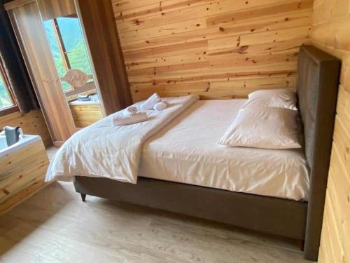 uma cama num quarto com uma parede de madeira em KIRSULA DAĞ EVİ em Çamlıhemşin