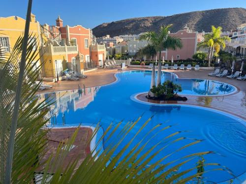 een zwembad in een resort met palmbomen en gebouwen bij penthouse with great sea view and natural reserve - magnificent swimming pool - calm and bright in Palm-mar