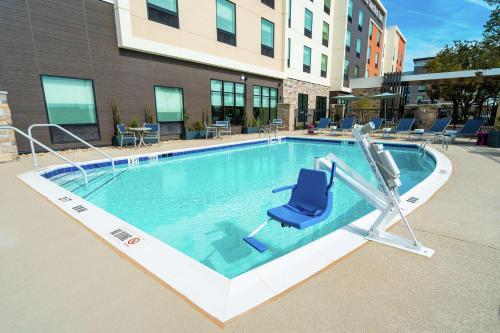 a swimming pool with a blue chair in a building at Hilton Garden Inn Cedar Park Austin in Austin