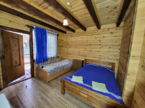 Blockhausschlafzimmer mit einem Bett und einem Fenster in der Unterkunft База відпочинку Діана in Szack