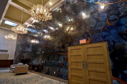 a room with a colorful wall with a cabinet and chandeliers at DoubleTree by Hilton Oceanfront Virginia Beach in Virginia Beach