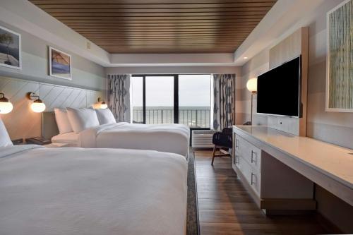 a hotel room with two beds and a flat screen tv at DoubleTree by Hilton Oceanfront Virginia Beach in Virginia Beach