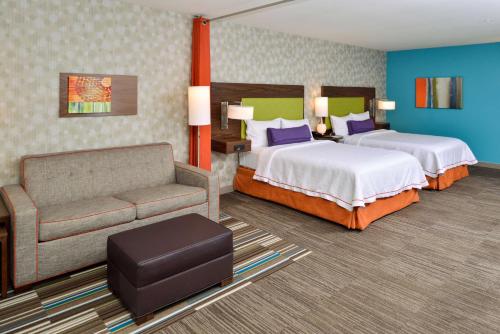 a hotel room with two beds and a couch at Home2 Suites By Hilton Portland Hillsboro in Hillsboro