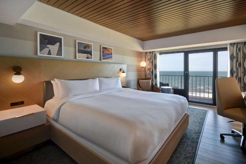 バージニアビーチにあるDoubleTree by Hilton Oceanfront Virginia Beachの大きなベッドとバルコニーが備わるホテルルームです。