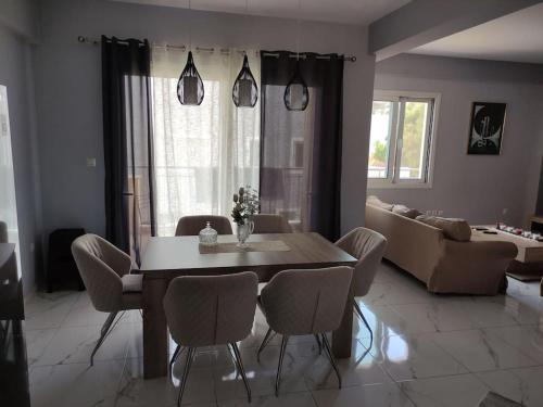 een woonkamer met een tafel en stoelen en een bank bij Modern Seaside Apartment in Artemida