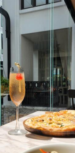 a glass of wine next to a pizza on a table at Mövenpick Hotel Sukhumvit 15 Bangkok in Bangkok
