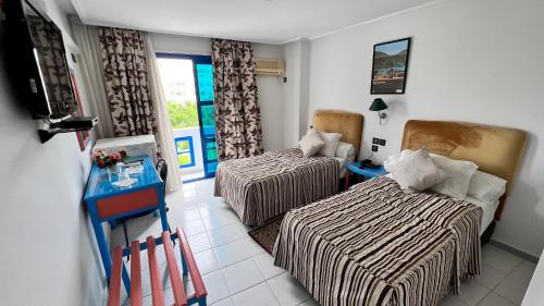 Zimmer mit 2 Betten, einem Tisch und einem Fenster in der Unterkunft Hotel Annakhil in Nador