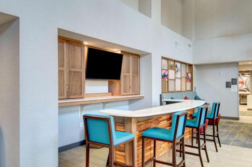 a kitchen with a bar with chairs and a tv at Hampton Inn & Suites Portland West in Portland