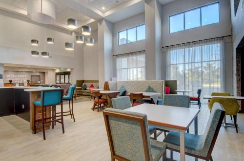 a waiting room with tables and chairs and windows at Hampton Inn & Suites Portland West in Portland