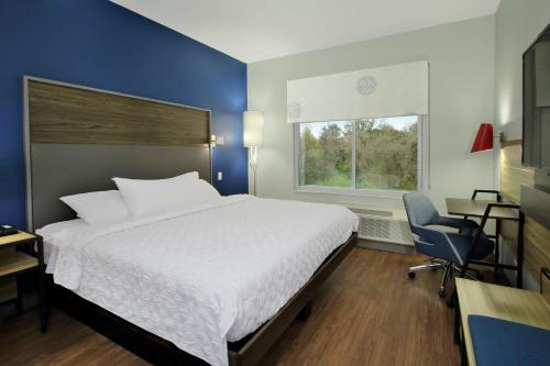 a bedroom with a bed and a chair and a window at Tru By Hilton Mobile in Mobile