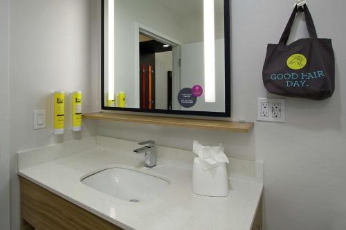 a bathroom with a sink and a mirror and a bag at Tru By Hilton Mobile in Mobile