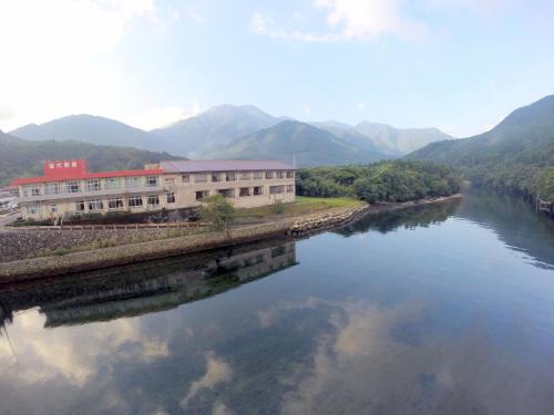 a building on the side of a river with mountains at Tashiro Annex in Yakushima