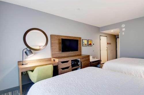 a hotel room with two beds and a desk with a mirror at Hampton Inn & Suites Portland West in Portland