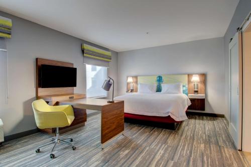 a hotel room with a bed and a desk and a tv at Hampton Inn & Suites Portland West in Portland