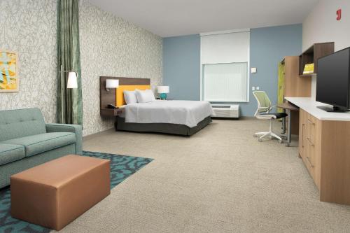 a hotel room with a bed and a flat screen tv at Home2 Suites By Hilton St. Augustine I-95 in St. Augustine