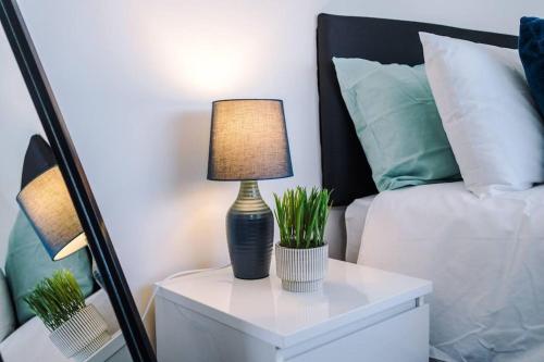 a lamp on a white table next to a bed at Beautiful apartment tres - free public parking in Litherland
