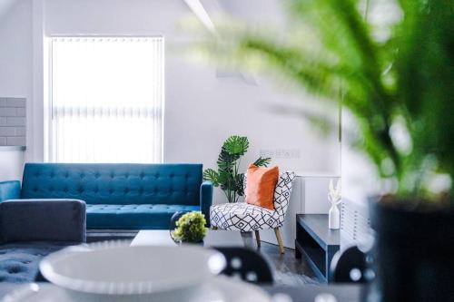 een woonkamer met een blauwe bank en een stoel bij Beautiful apartment una in Litherland