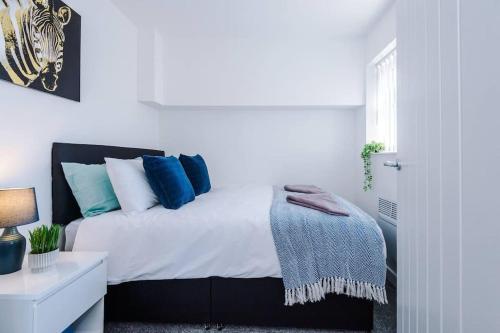 a white bedroom with a bed with blue pillows at Beautiful apartment tres - free public parking in Litherland
