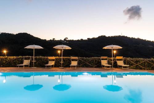 a swimming pool with chairs and umbrellas and a table at Villa Ginevra Resort Agrituristico in Ficarra