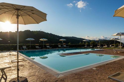 a swimming pool with an umbrella and chairs and tables at Villa Ginevra Resort Agrituristico in Ficarra