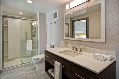 y baño con lavabo, aseo y espejo. en Home2 Suites By Hilton Taylor Detroit, en Taylor