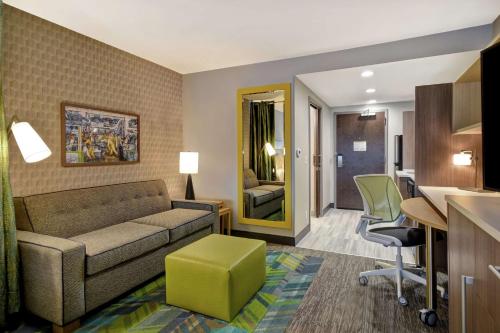a living room with a couch and a table and chairs at Home2 Suites By Hilton Taylor Detroit in Taylor
