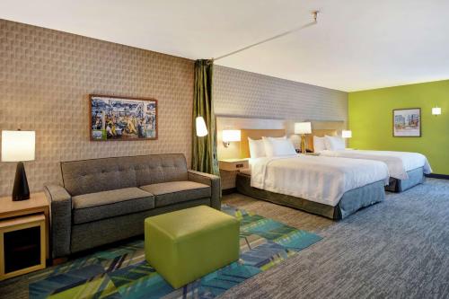テイラーにあるHome2 Suites By Hilton Taylor Detroitのベッド2台とソファが備わるホテルルームです。