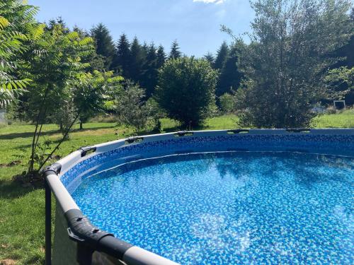 a large pool with blue water in a yard at Au Pré Fleuri Eco Glamping in Le Lindois