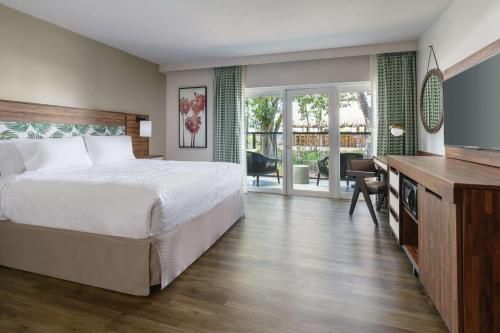 Hampton Inn Key West FL في كي ويست: غرفة نوم بسرير ومكتب مع تلفزيون