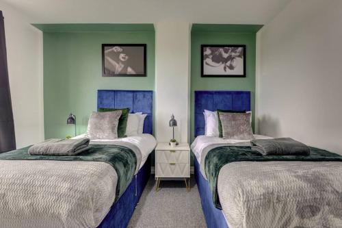 2 camas en una habitación con paredes azules y verdes en Sleek and Stylish 3 Bed House In Central Hull, en Hull